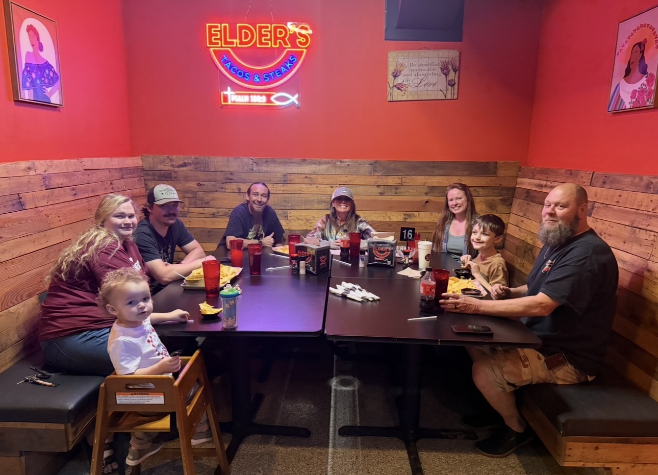 Family gathered around a booth under the Elder's neon sign
