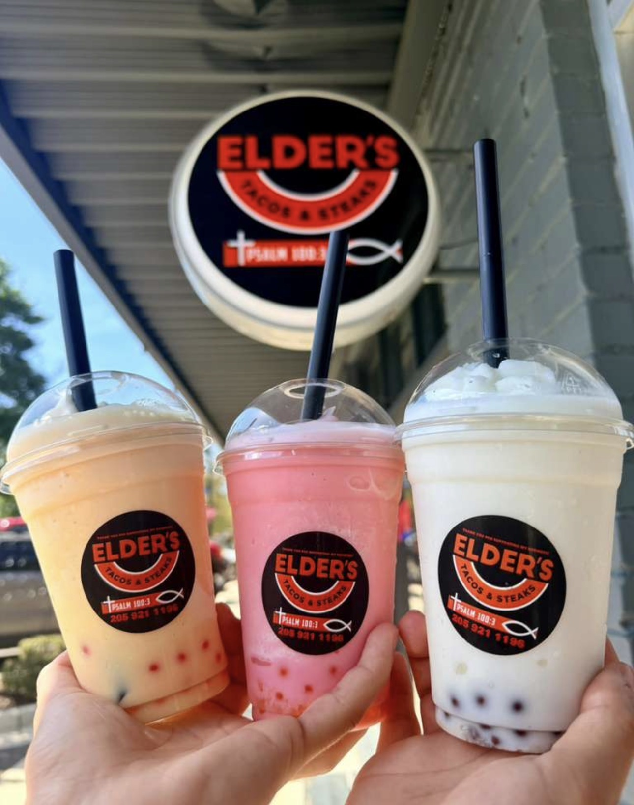 Three bubble teas in front of the Elder's Tacos & Steaks storefront sign