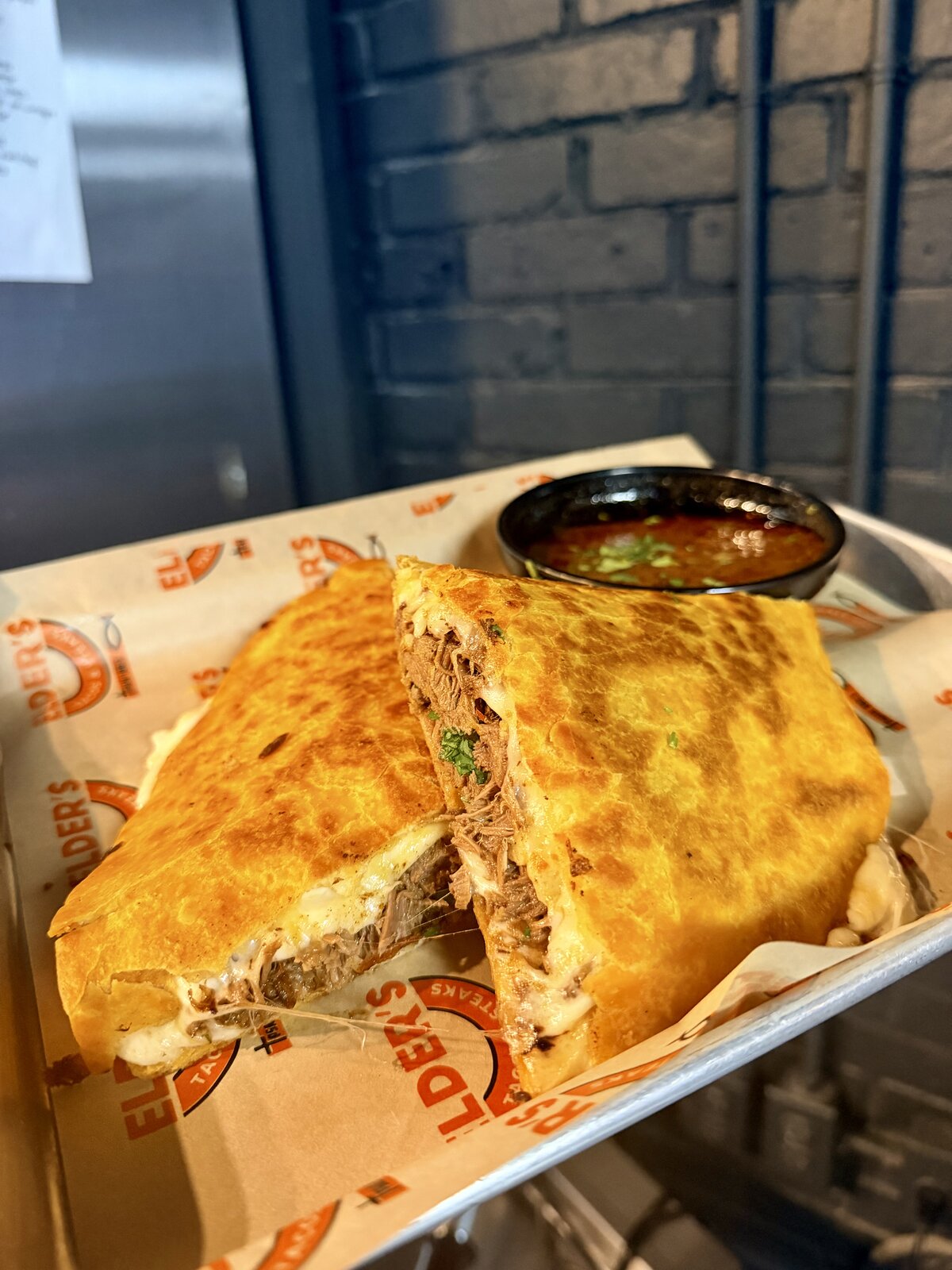 Golden birria melt with shredded beef and melted cheese, served with consomé