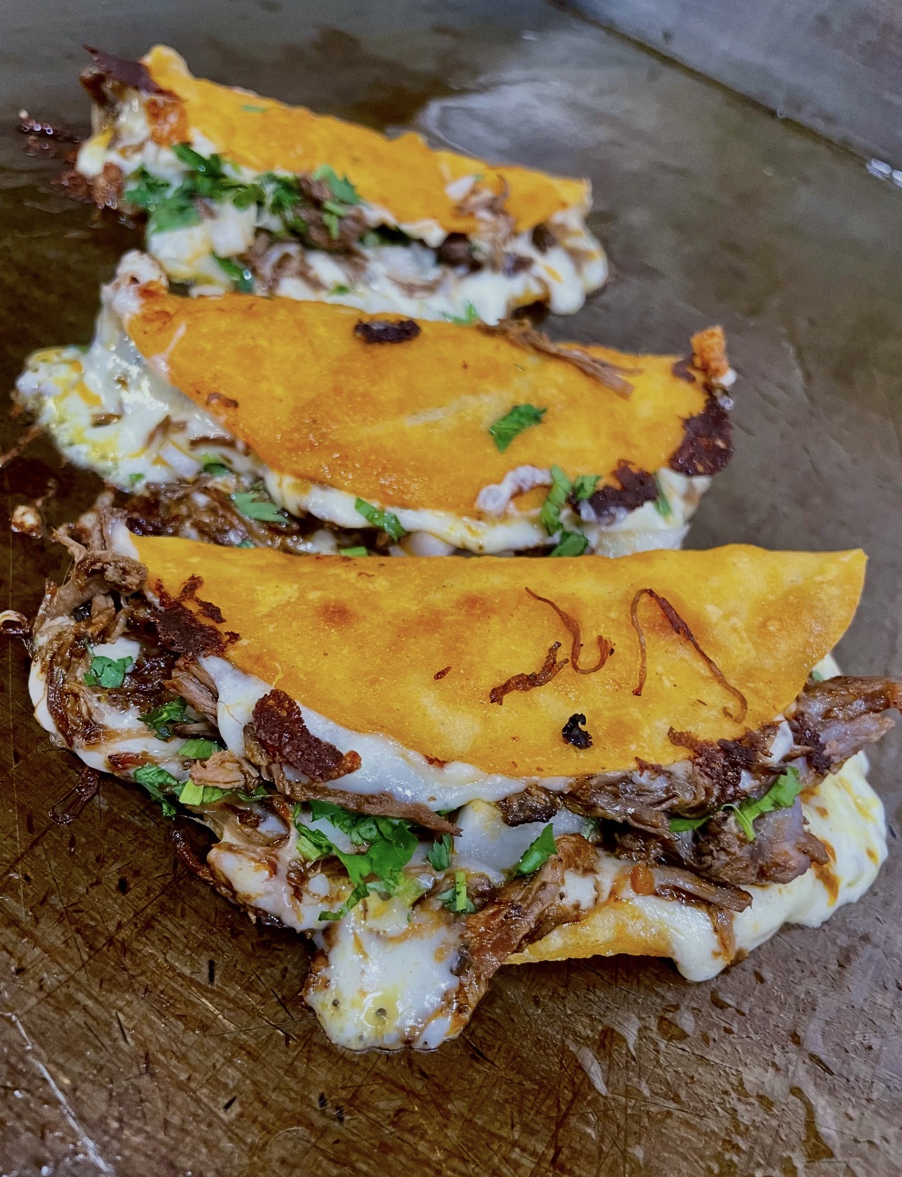 Crispy birria tacos with melted cheese and cilantro