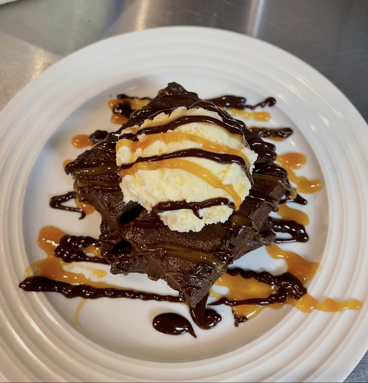 Warm brownie topped with vanilla ice cream, chocolate and caramel