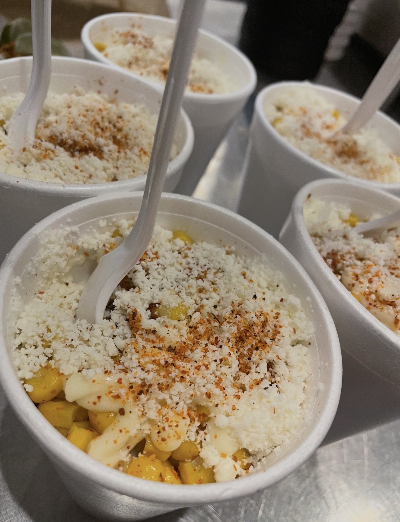Cups of elote topped with cotija cheese and chili powder