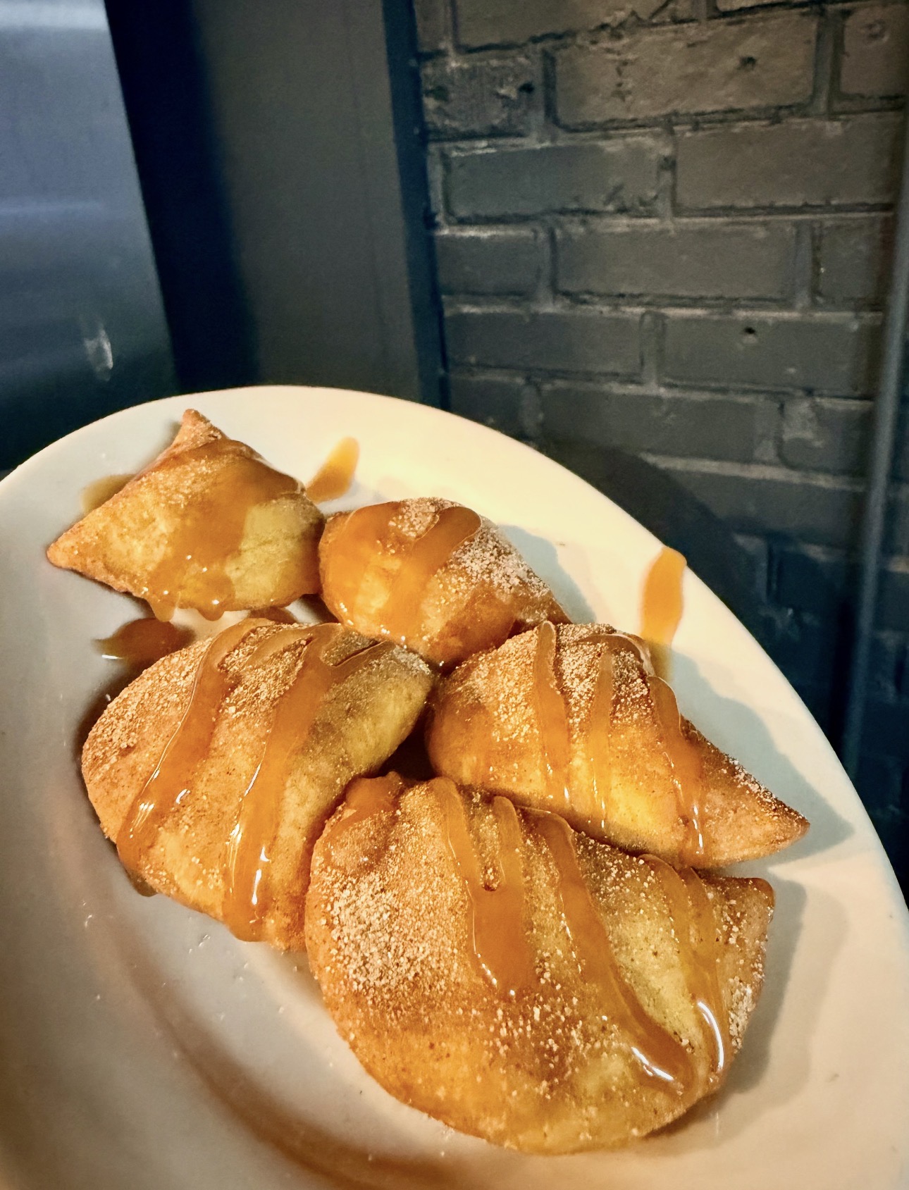 Golden fried empanadas dusted with cinnamon sugar and caramel drizzle