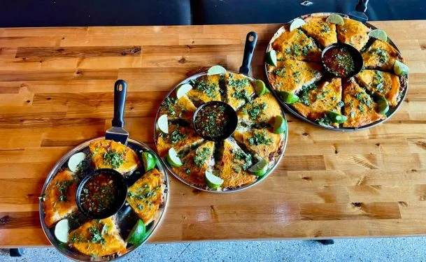 Three plates of mulitas with salsa and lime wedges