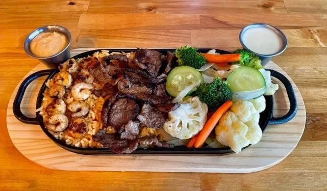 Sizzling surf & turf platter with steak, shrimp and veggies