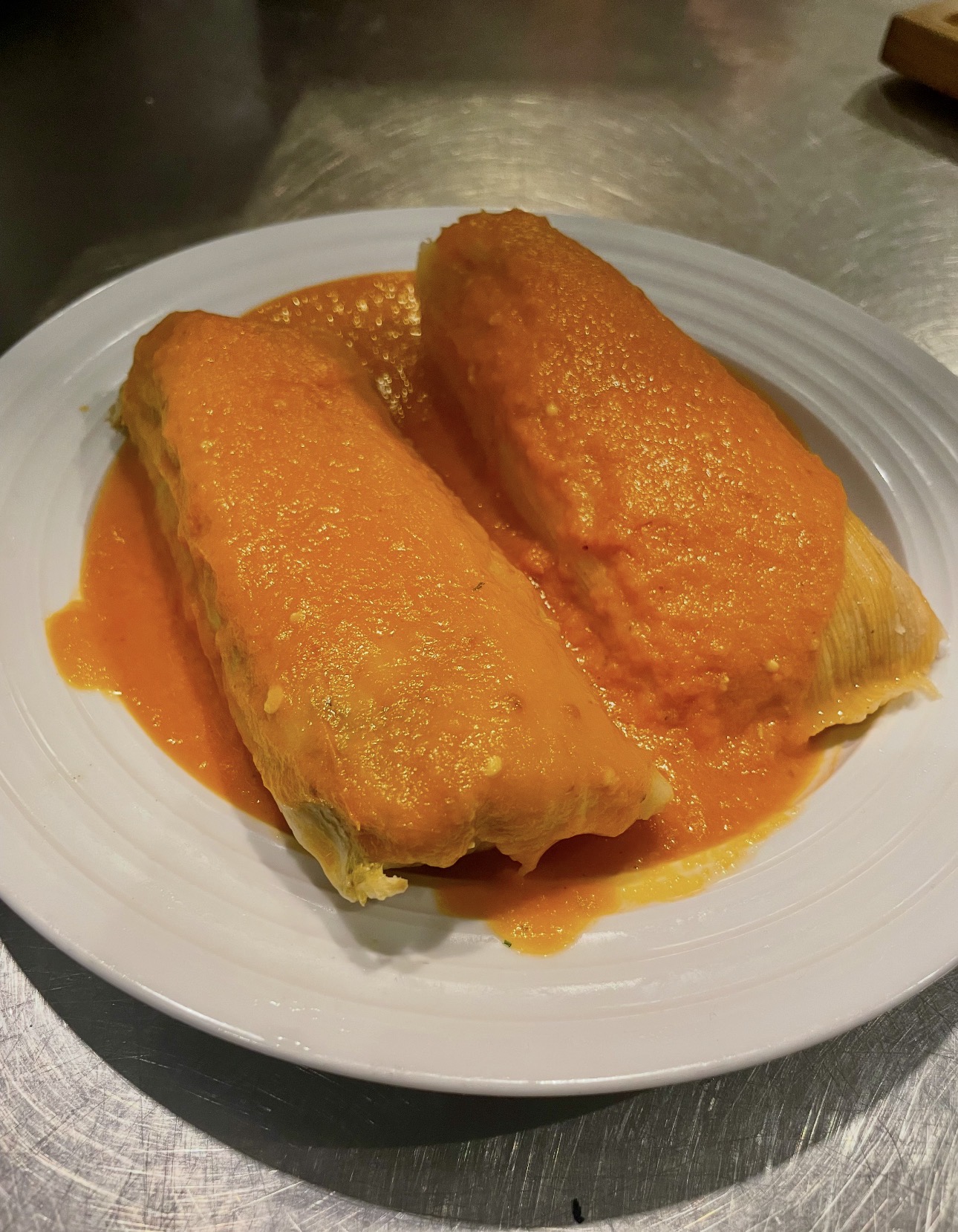 Two tamales smothered in bright red salsa
